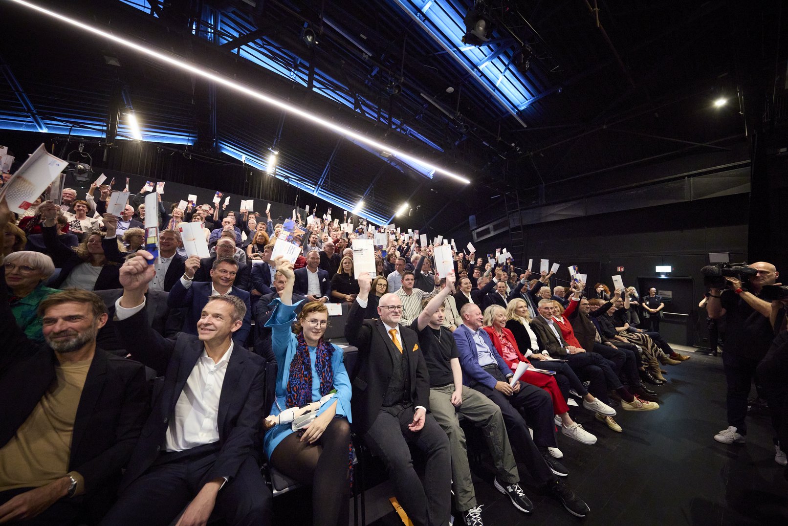 Ein Foto von der Abstimmung zum Fußball-Spruch des Jahres. Gäste der Gala, die im Zuschauerraum sitzen, heben das Programm als Zeichen der Abstimmung in die Höhe.