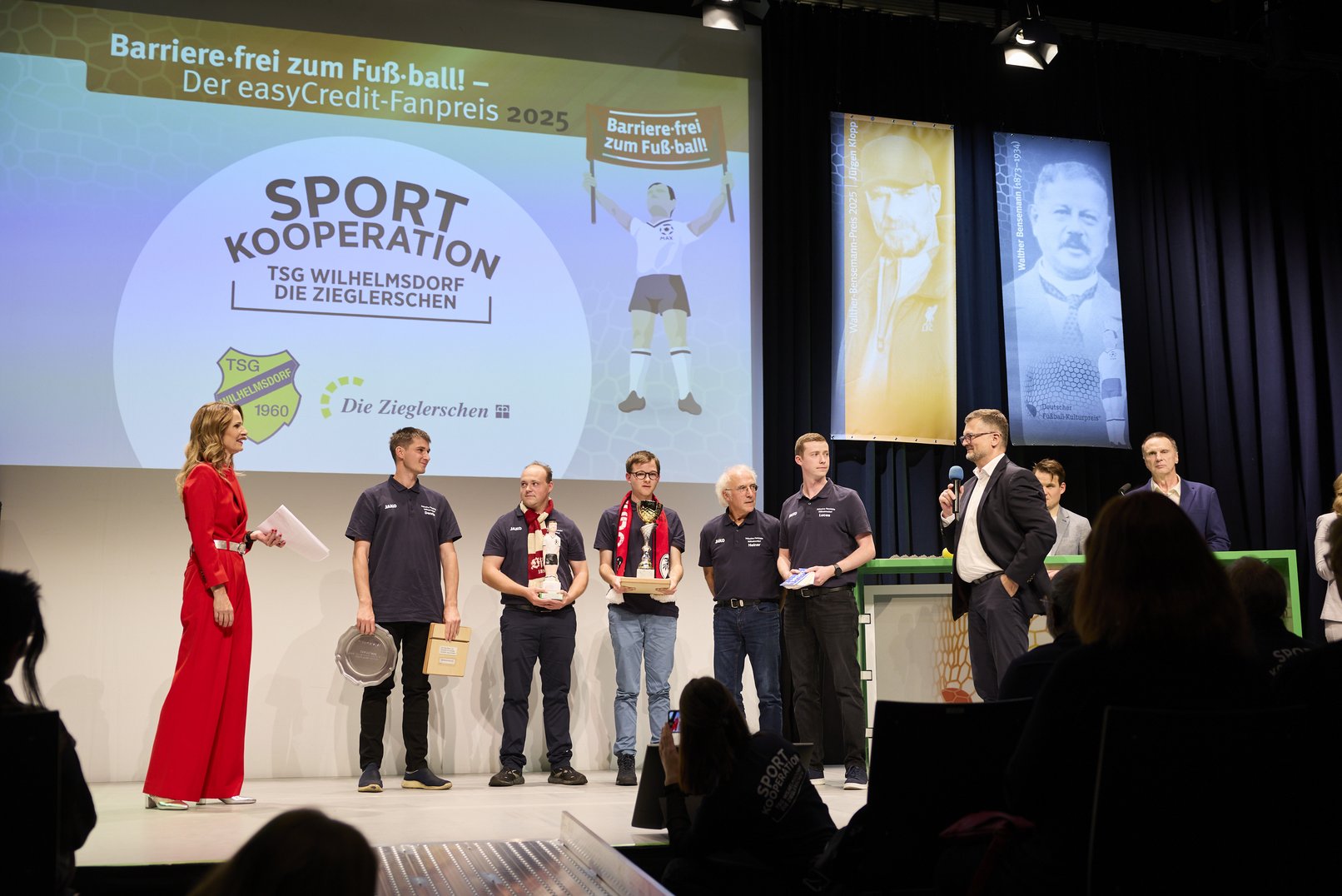 5 Personen der TSG Wilhelmsdorf / Die Zieglersche, die den Fanpreis gewonnen haben, stehen auf der Bühne. Herr Polenz, Vertreter des Sponsors der teambank bedankt sich für die Teilnahme.